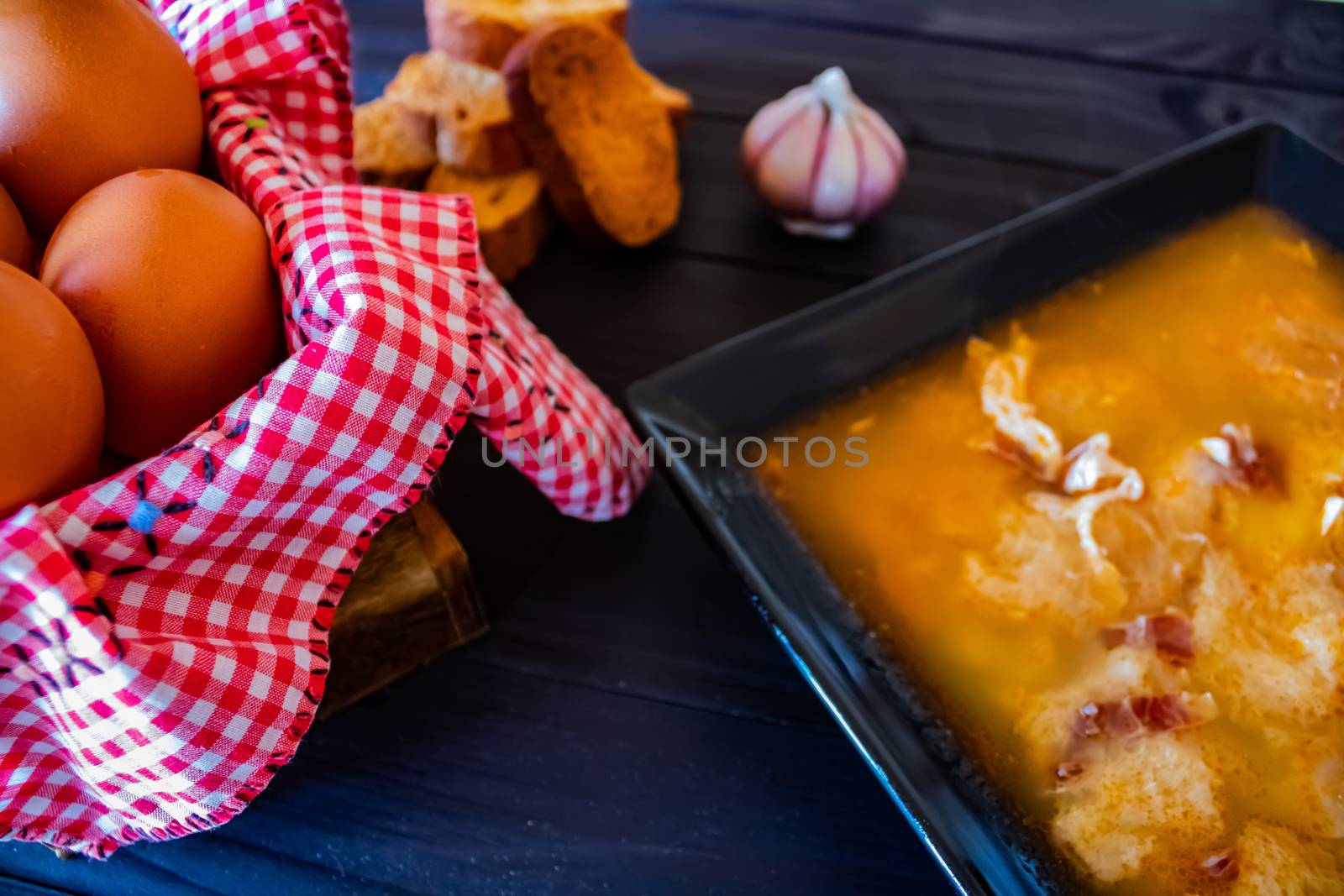 Typical Spanish garlic soups in composition on dark wood background