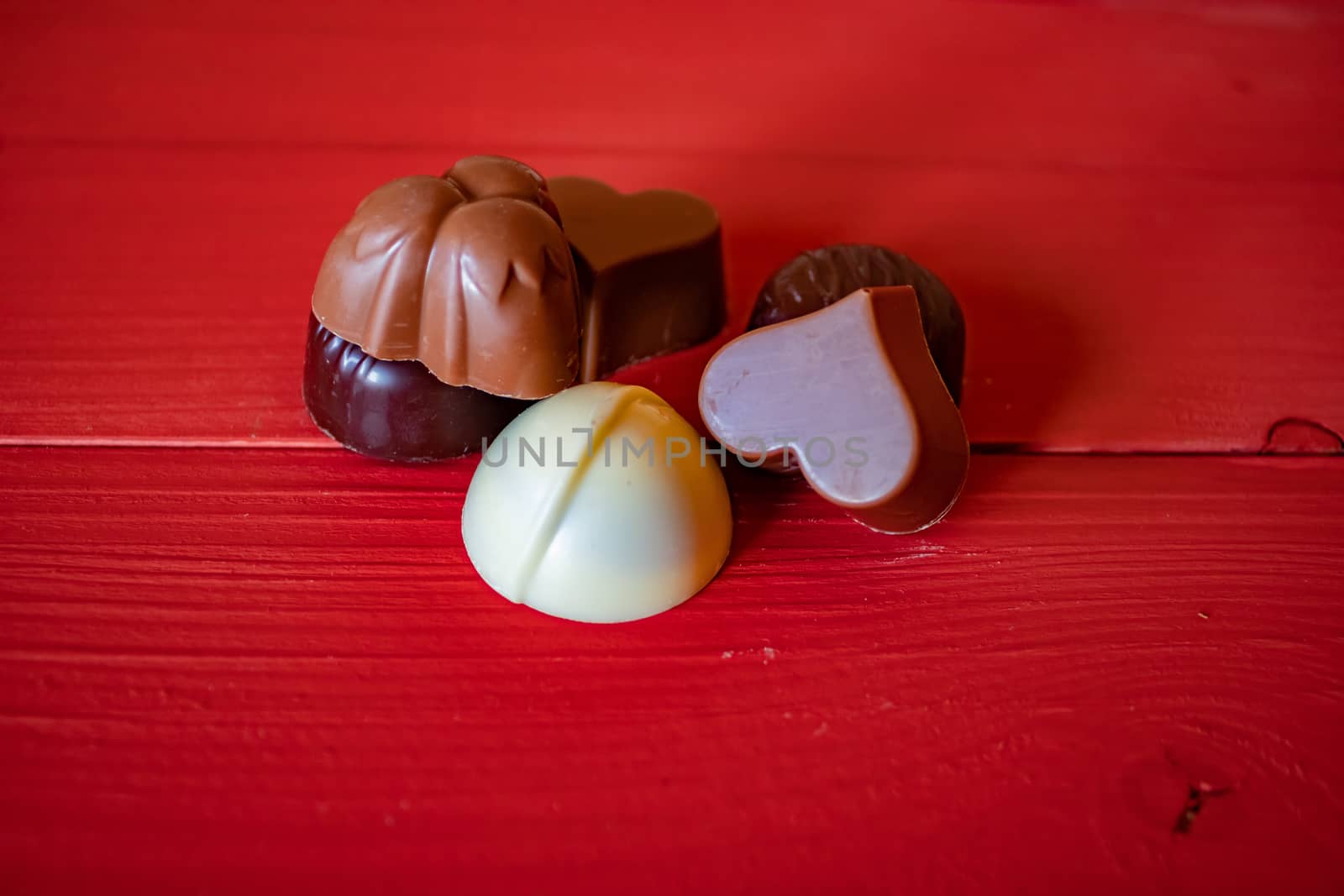 View of assorted chocolates on red wood background
