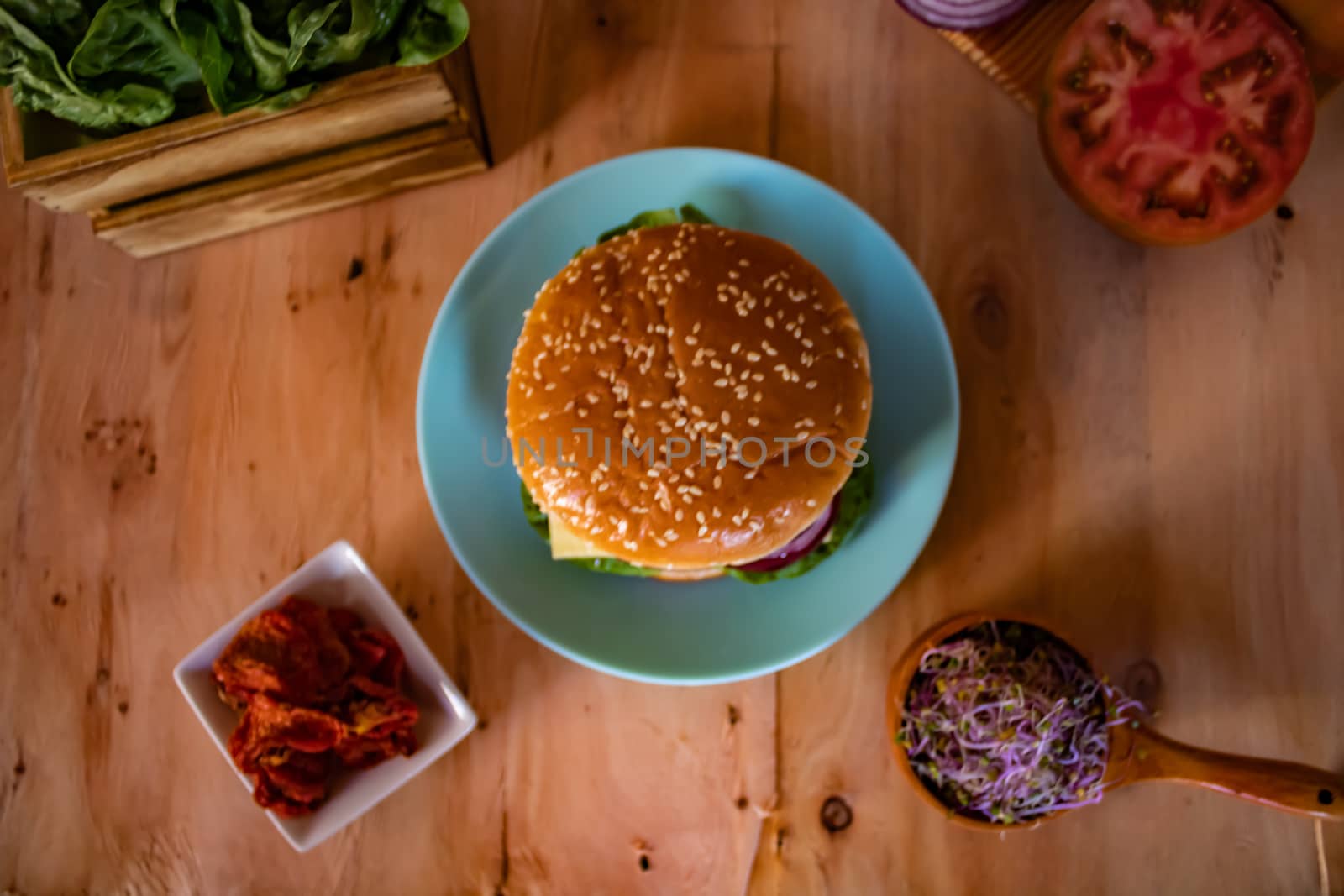 Hamburger and ingredients in composition on wooden background