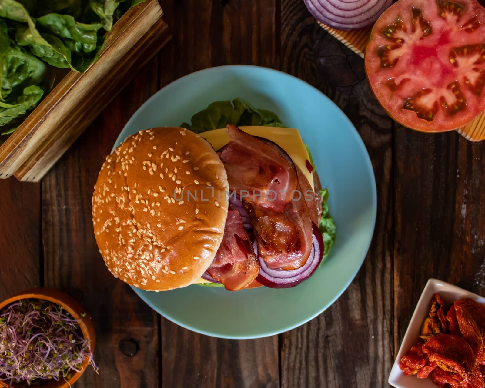Hamburger and ingredients in composition on wooden background