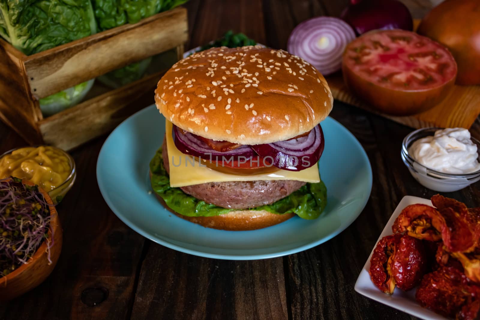 Hamburger and ingredients in composition on wooden background