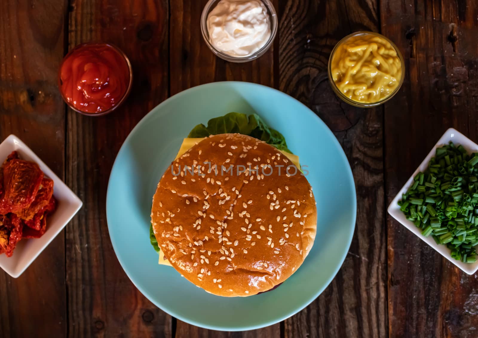 Hamburger and ingredients in composition on wooden background