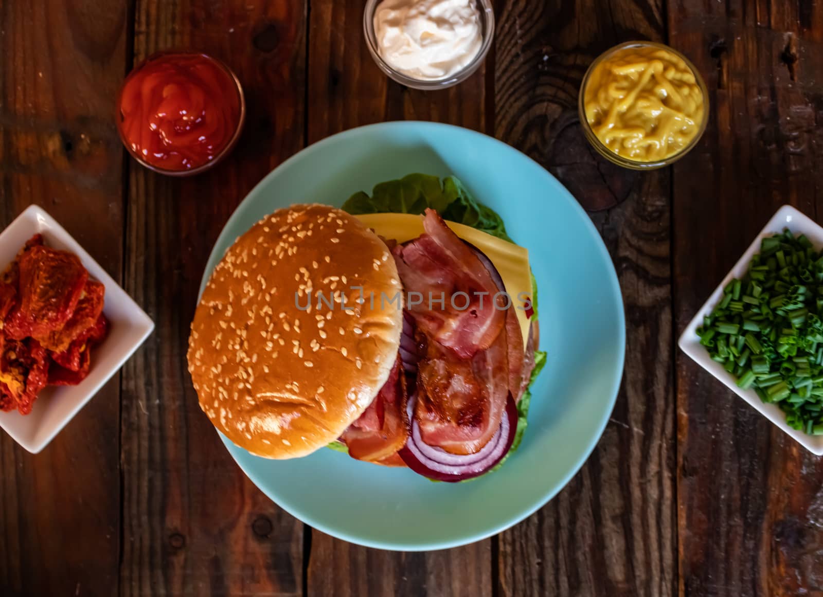 Hamburger and ingredients in composition on wooden background