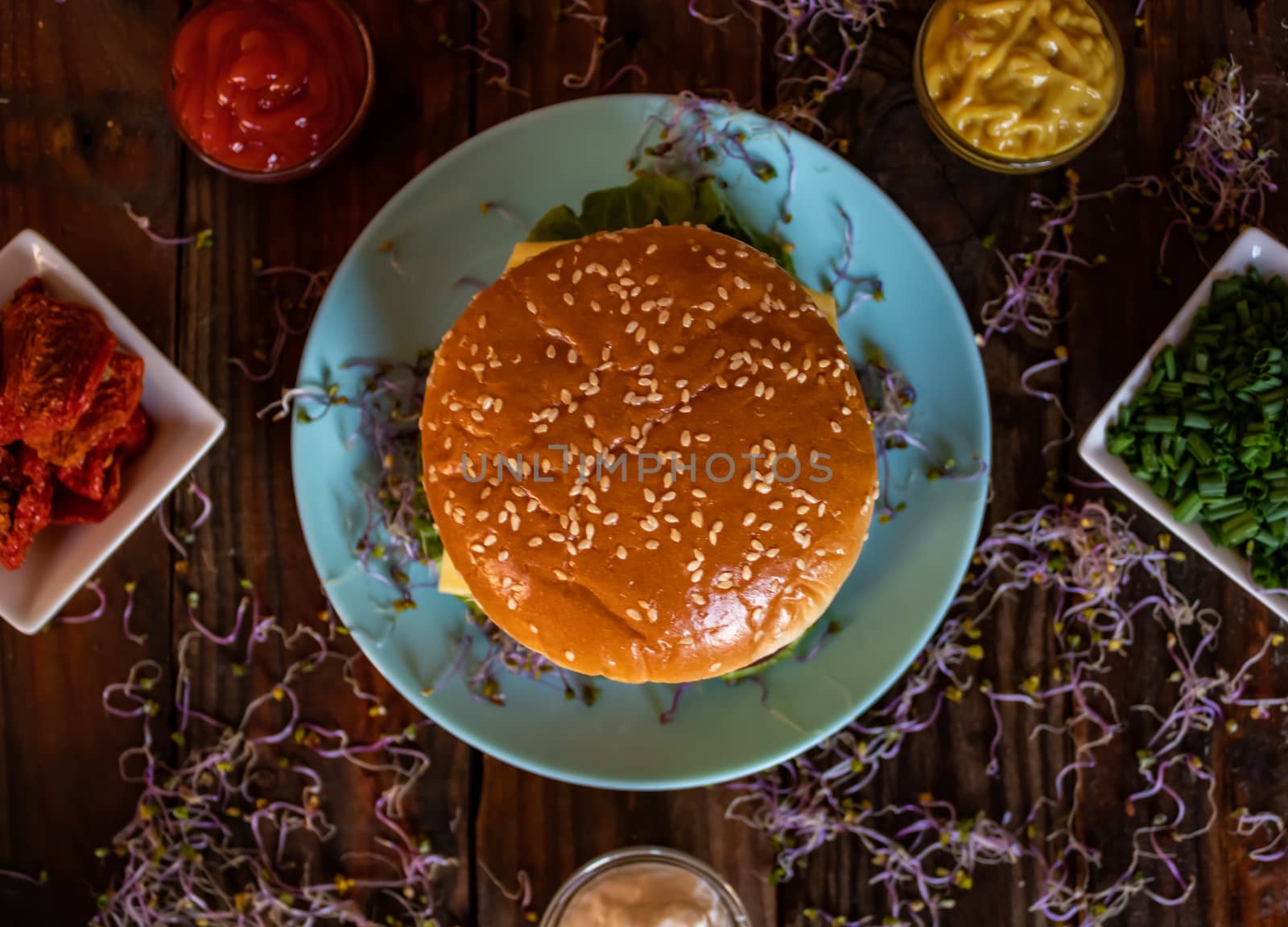 Hamburger and ingredients in composition on wooden background