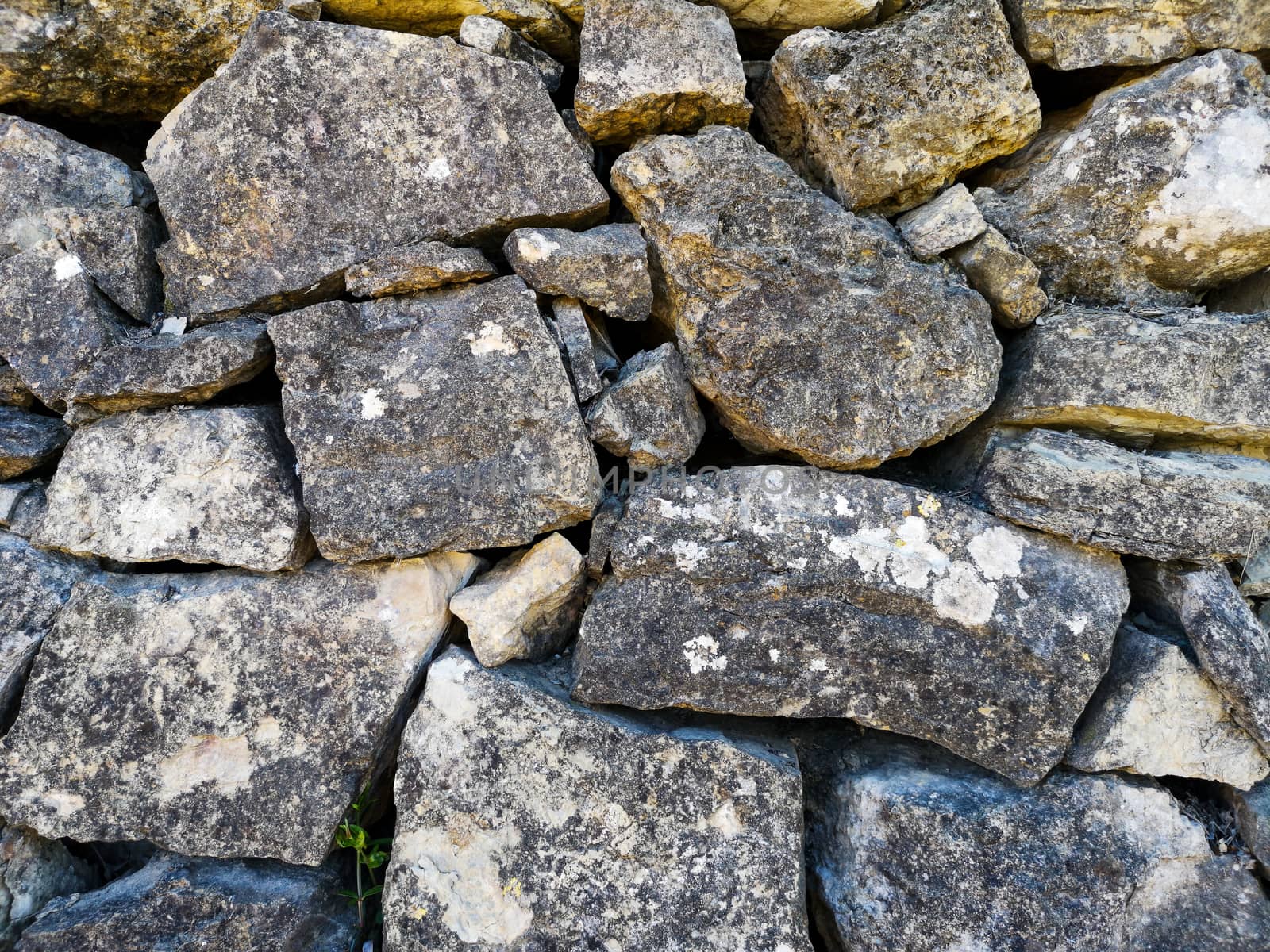 Wall of gray interspersed stones made by hand mind