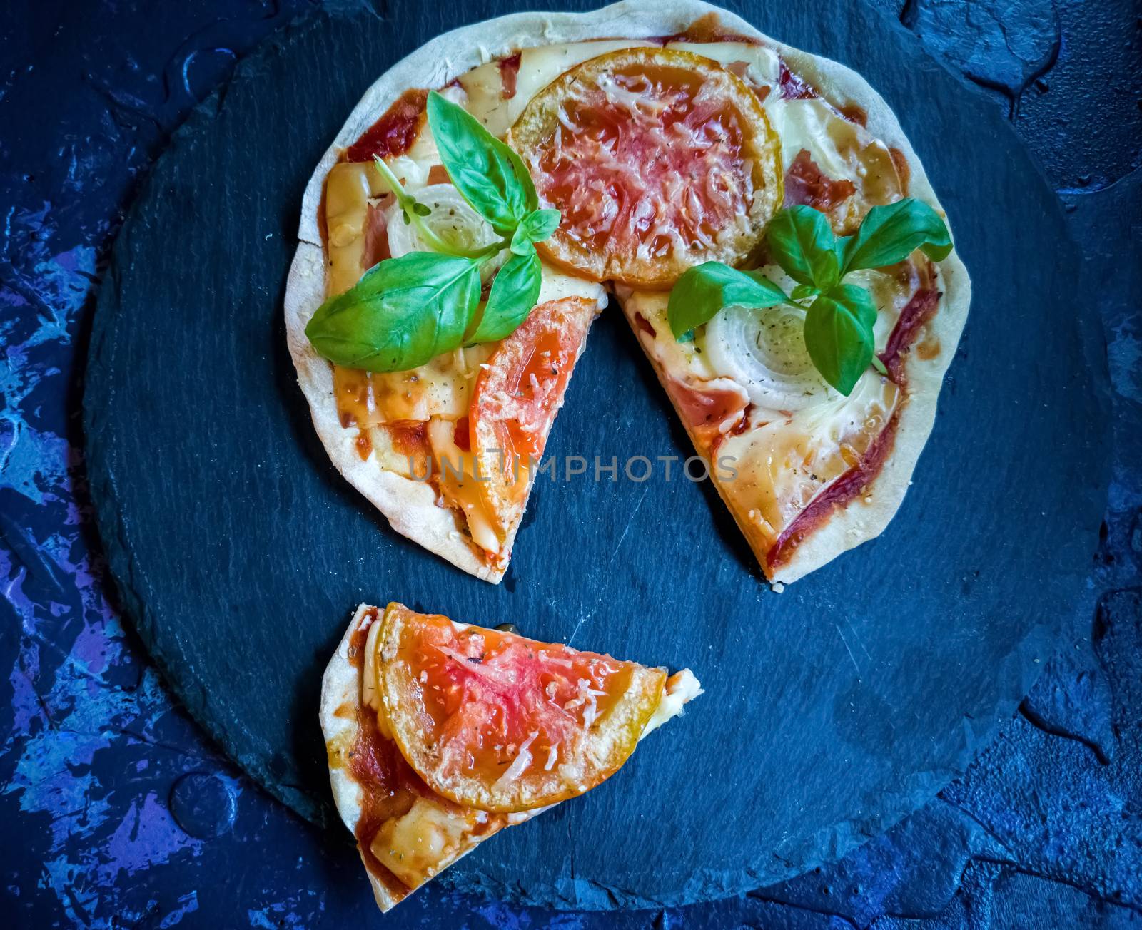 Homemade pizzas and utensils on dark background in lilac tones