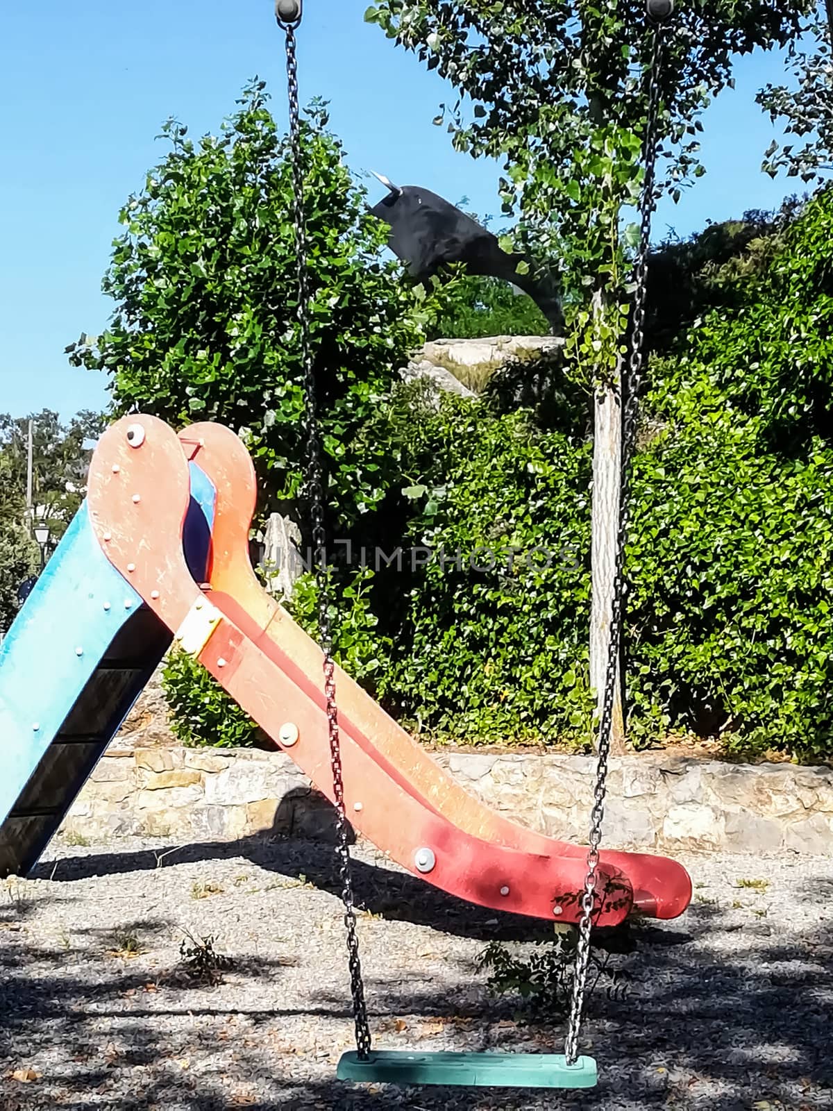 children playground with very colorful swings and some trees
