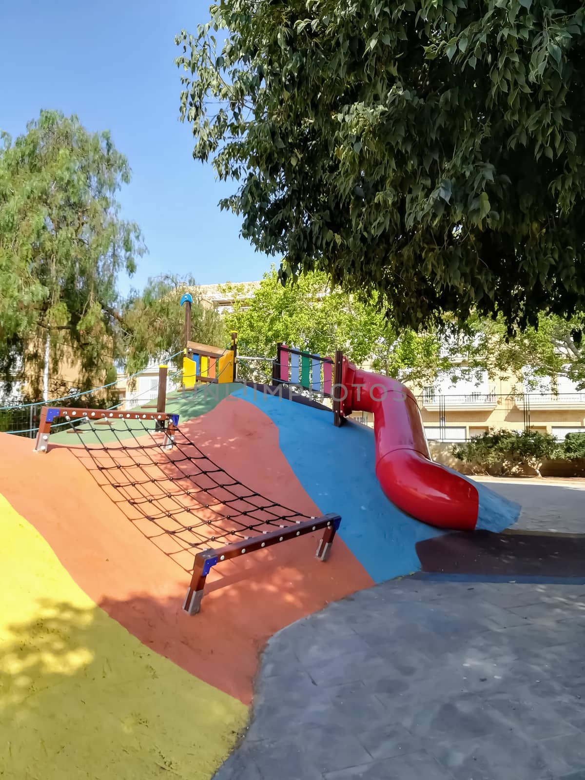 children playground with very colorful swings and some trees