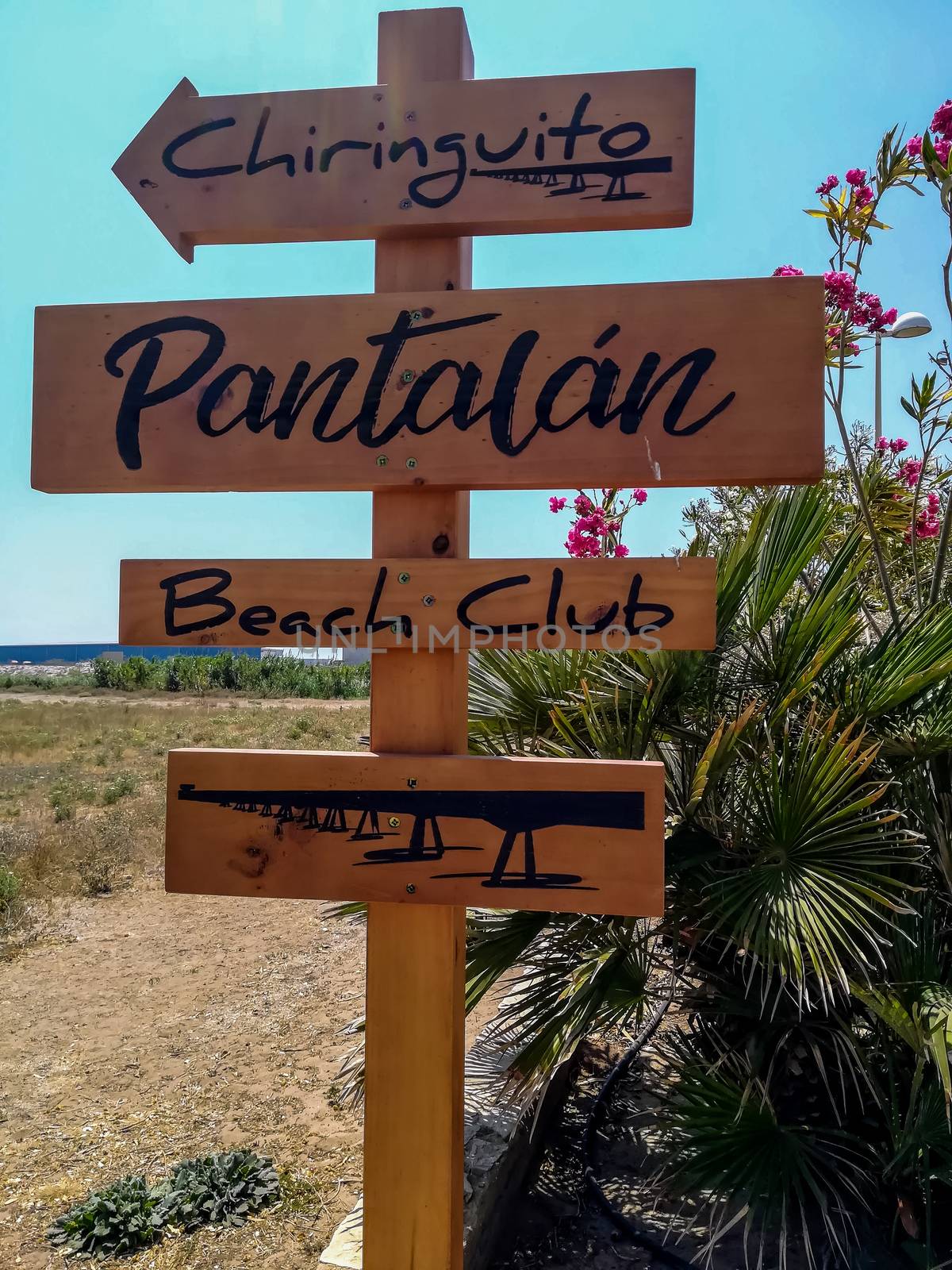 Wooden sign with arrows indicating the way to the beach of Puerto de Sagunto