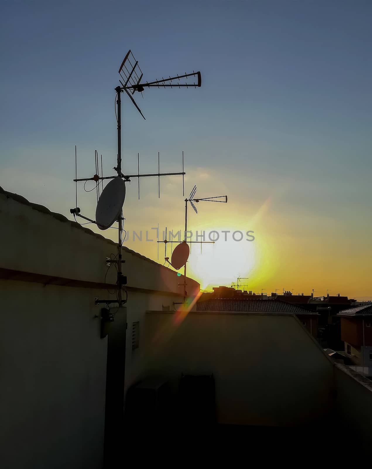 View of the sun setting from a terrace with several satellite dishes in Alquerias