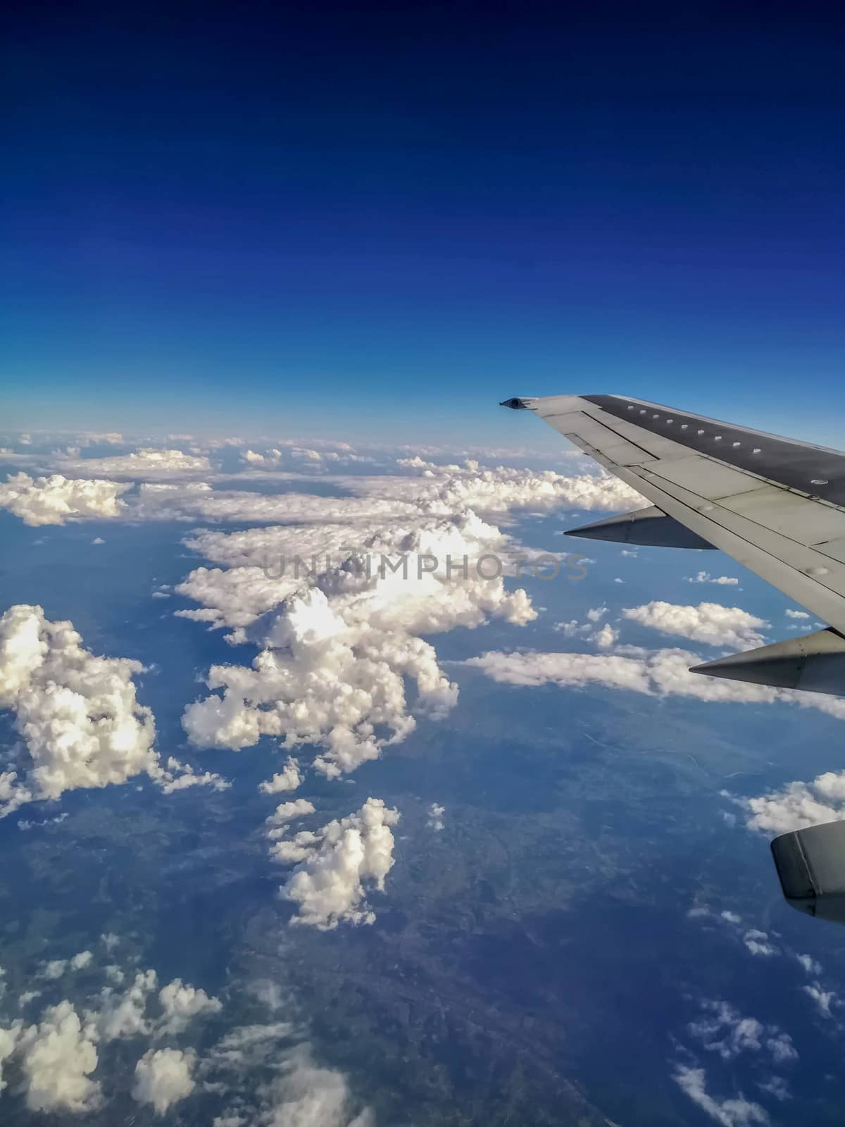 View of part of the wing and the sky with white clouds from an airplane