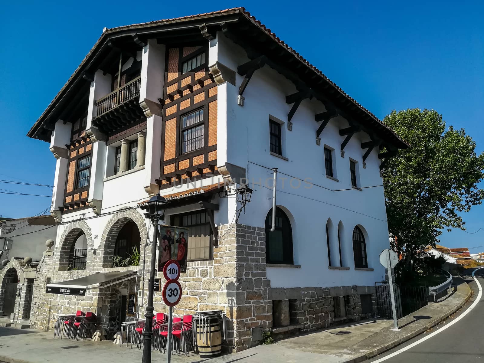 Nice white house with stone on the facade and roof with blue sky background