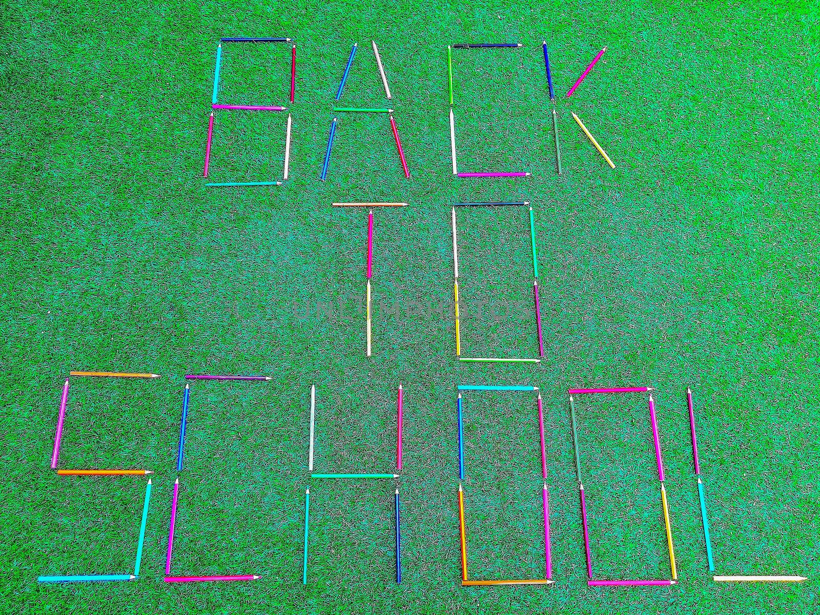 School material in composition on artificial grass background