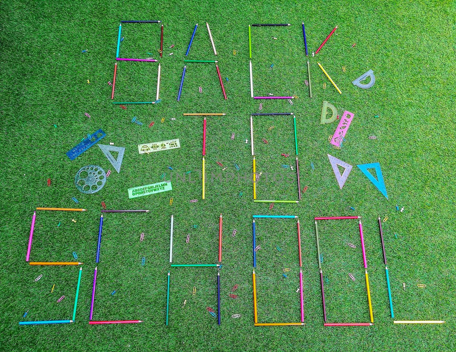 School material in composition on artificial grass background
