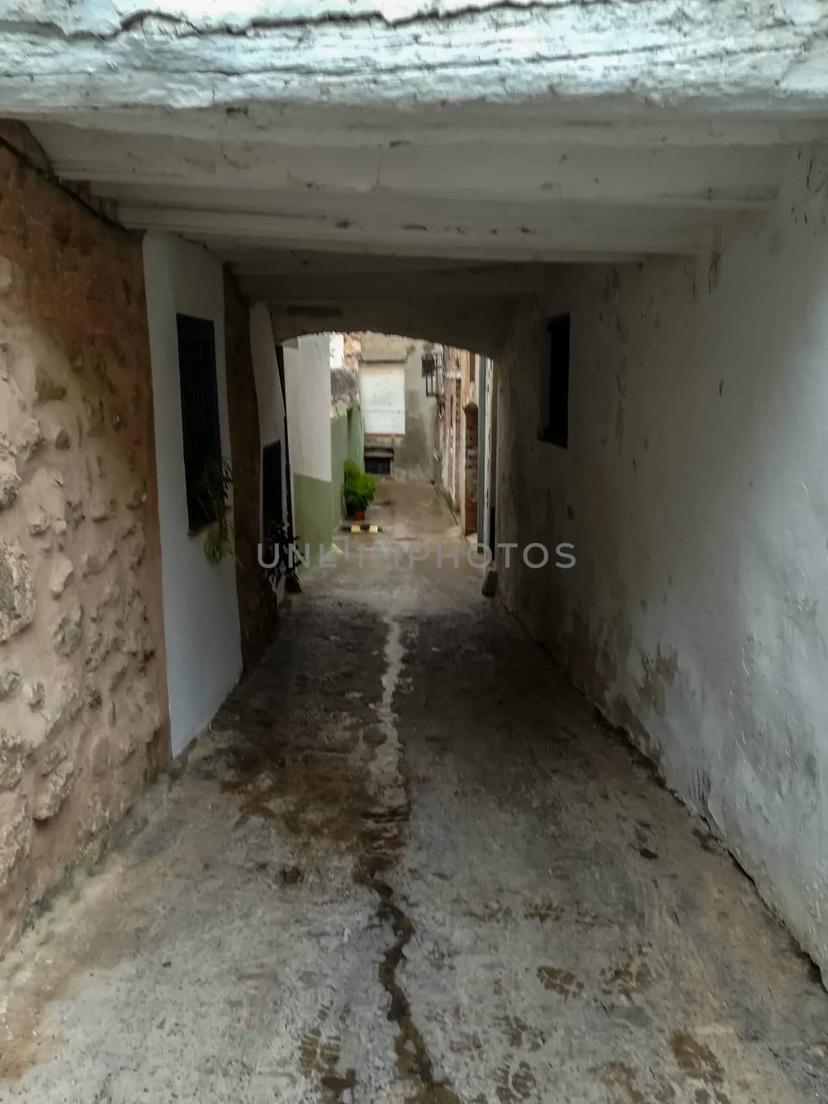 Old narrow street with a small white tunnel with large beams in Segorbe