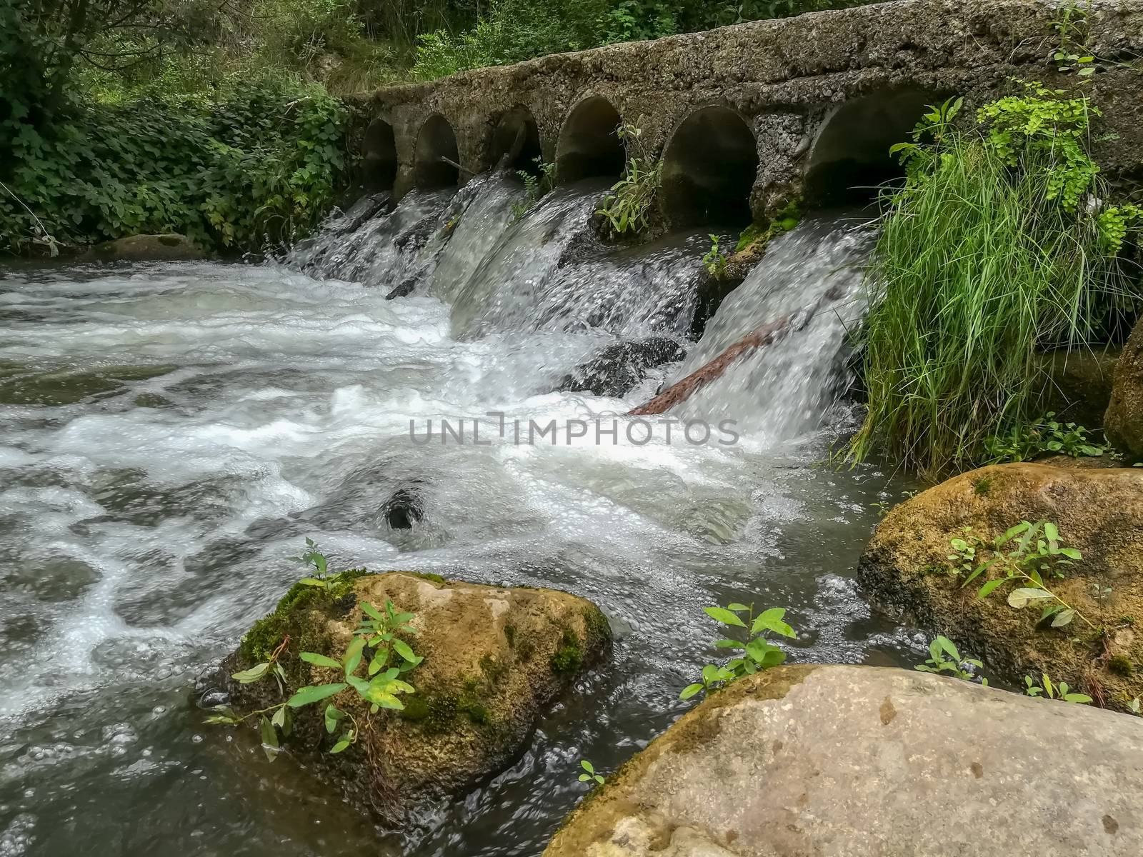 Bridge with water flowing through it by cylinders in Navajas