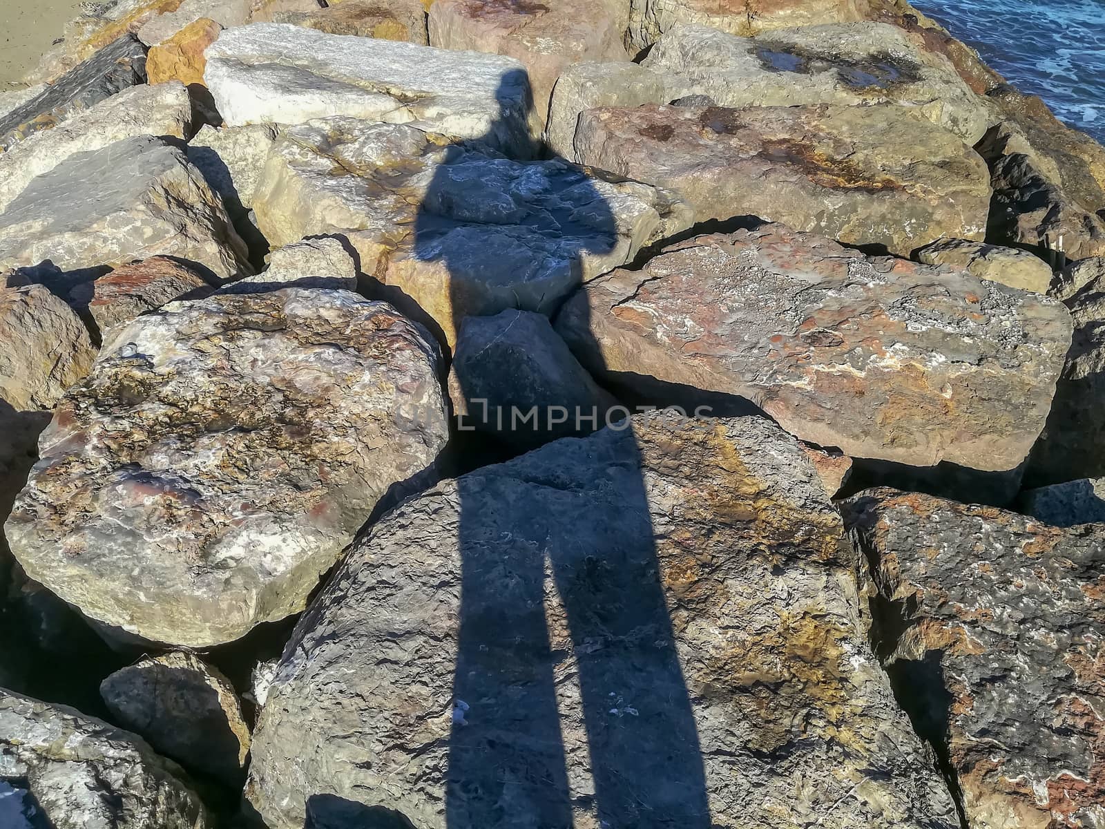 Shadow of spiky person on a breakwater in the Mediterranean Sea