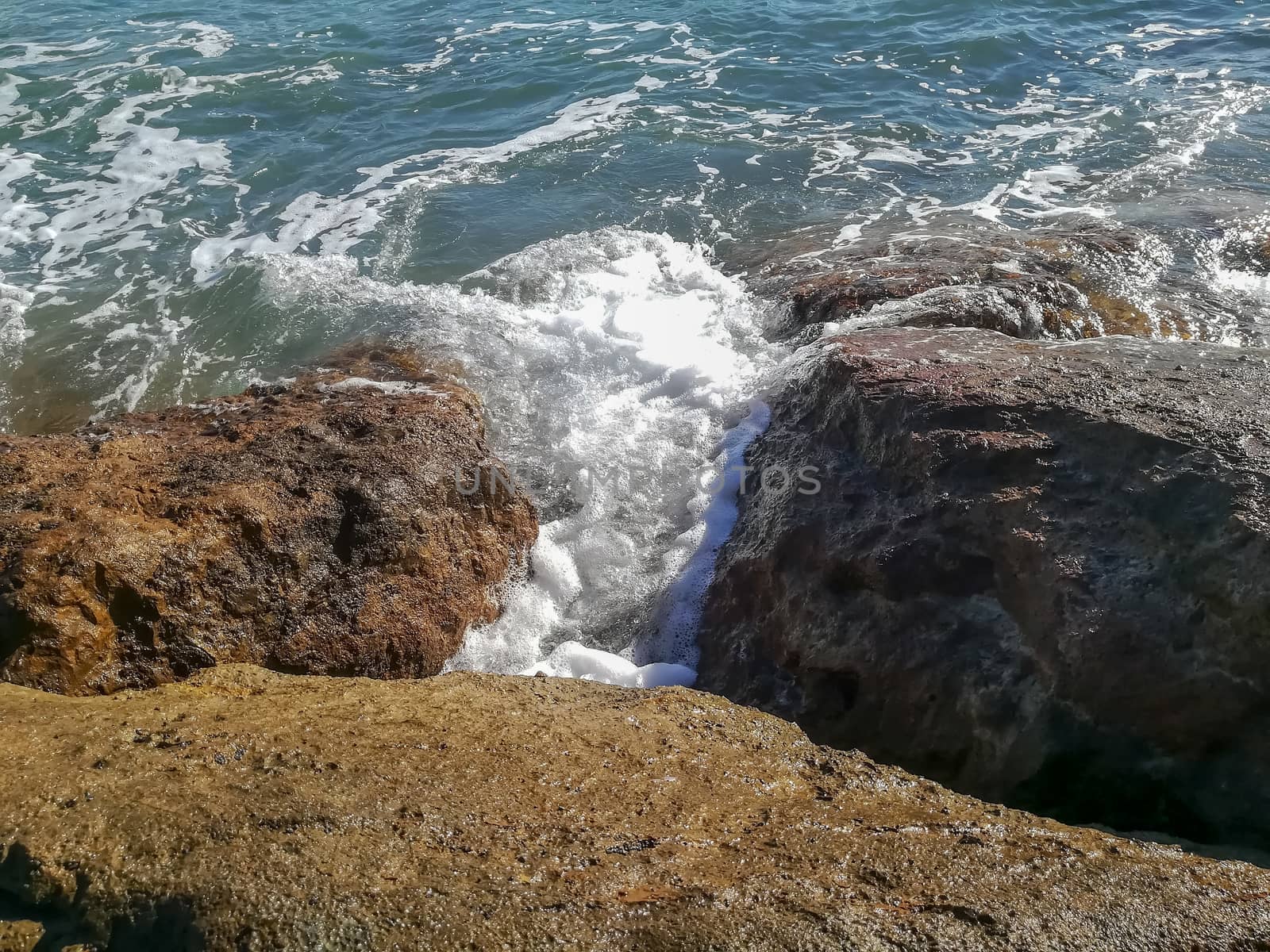 View of the Mediterranean sea breaking against the rocks generating sea foam