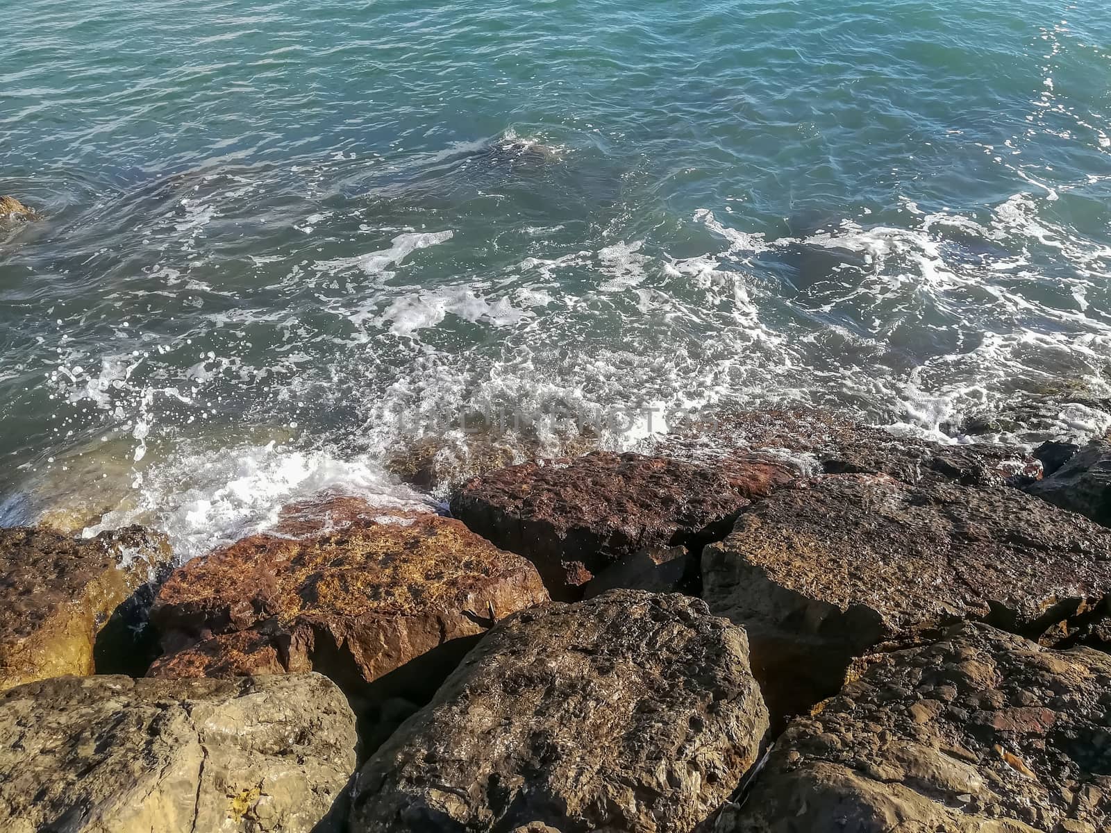 View of the Mediterranean sea breaking against the rocks generating sea foam