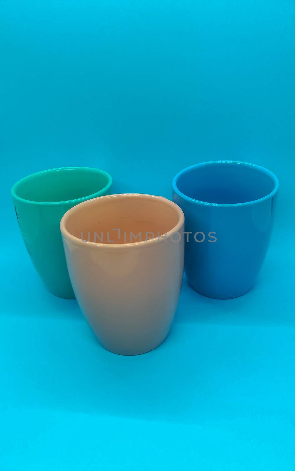 Colorful ceramic coffee cups on blue background