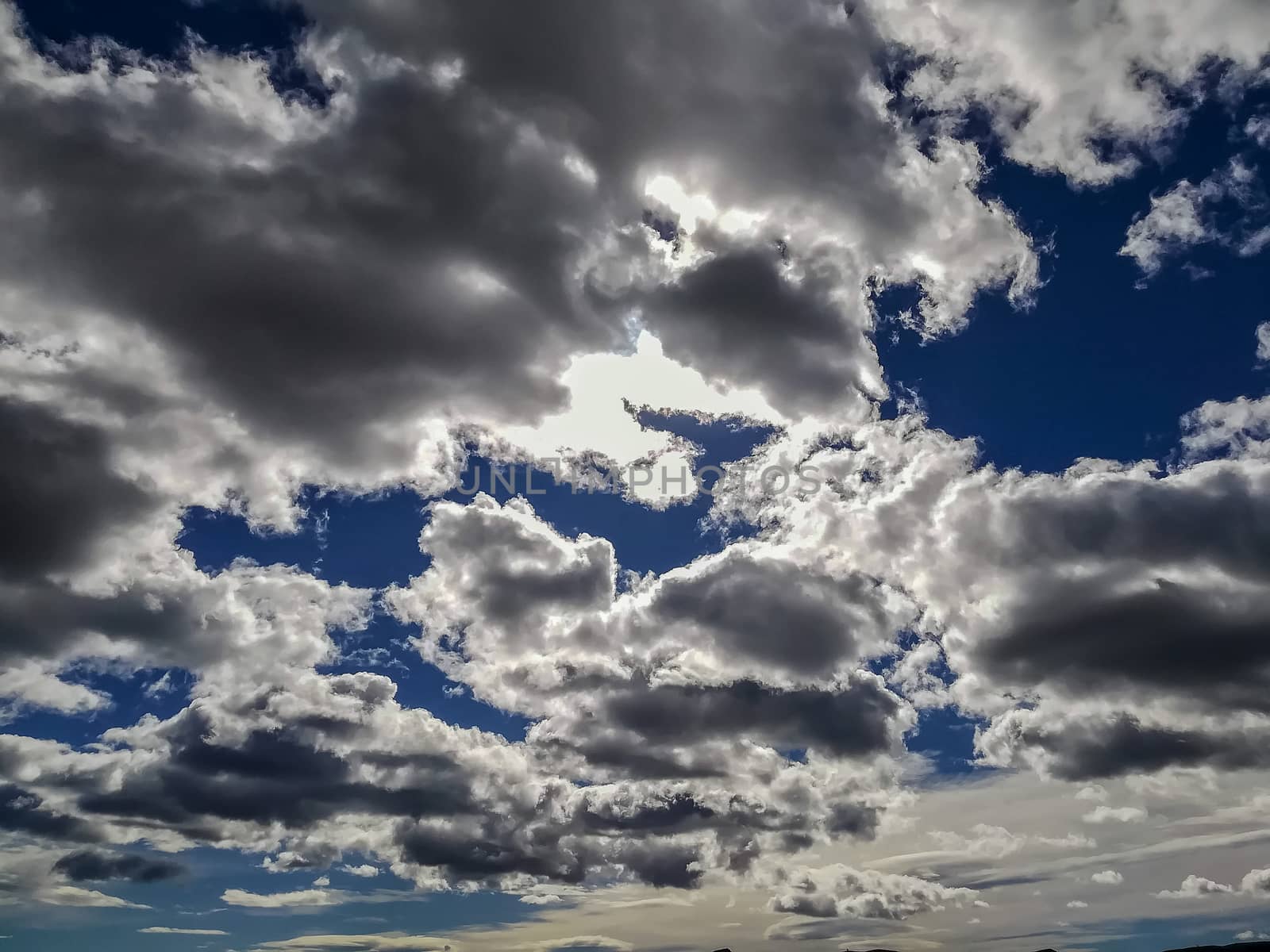 Sky with threatening storm clouds in various blue tones with sunlight through