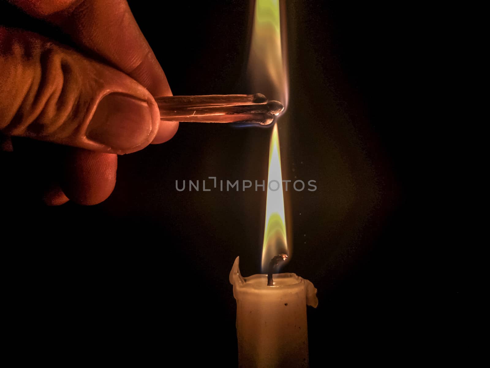 Matches burning to light a candle on black background