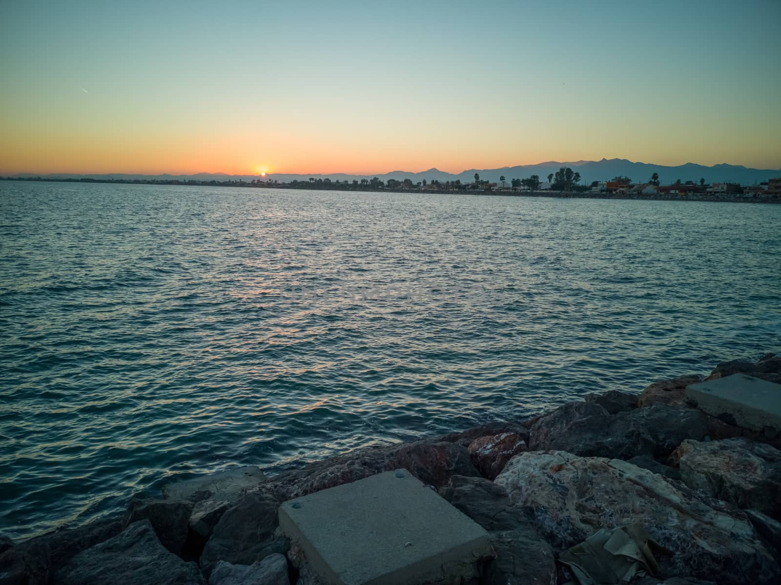 Sunset over the mountains seen from a breakwater of the Mediterranean Sea