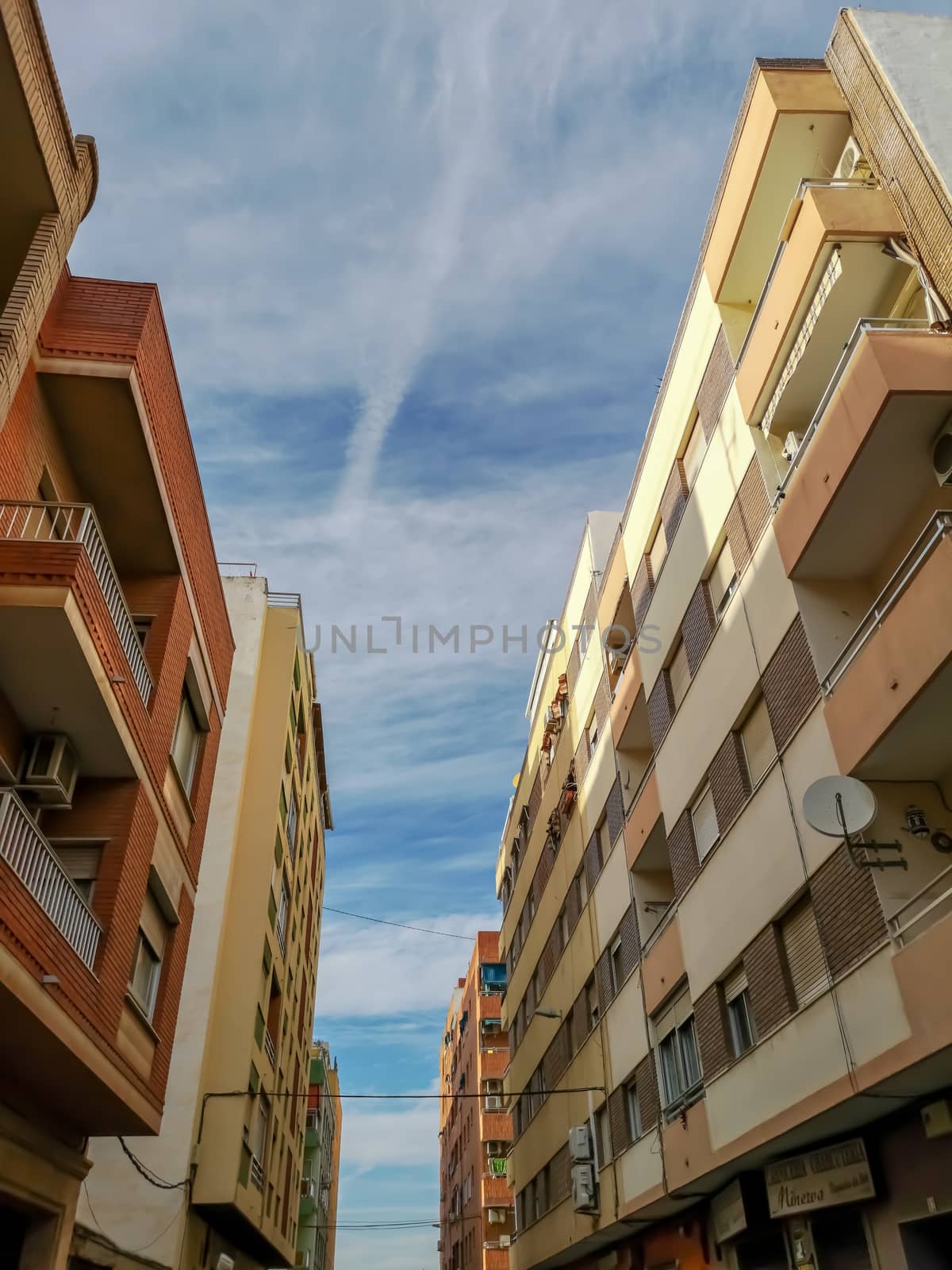 Street with different buildings in the Puerto de Sagunto with cloudy sky