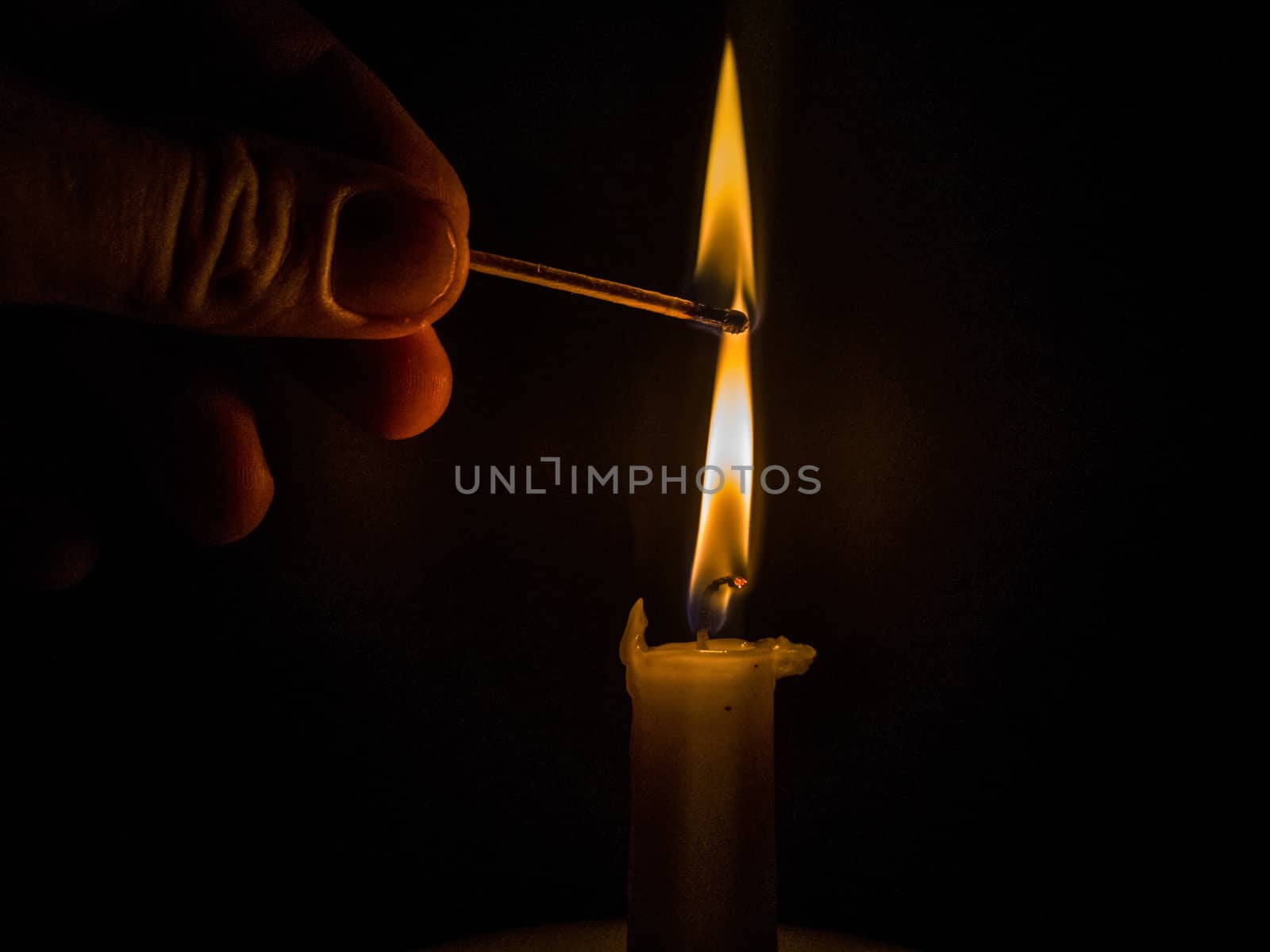 Matches burning to light a candle on black background