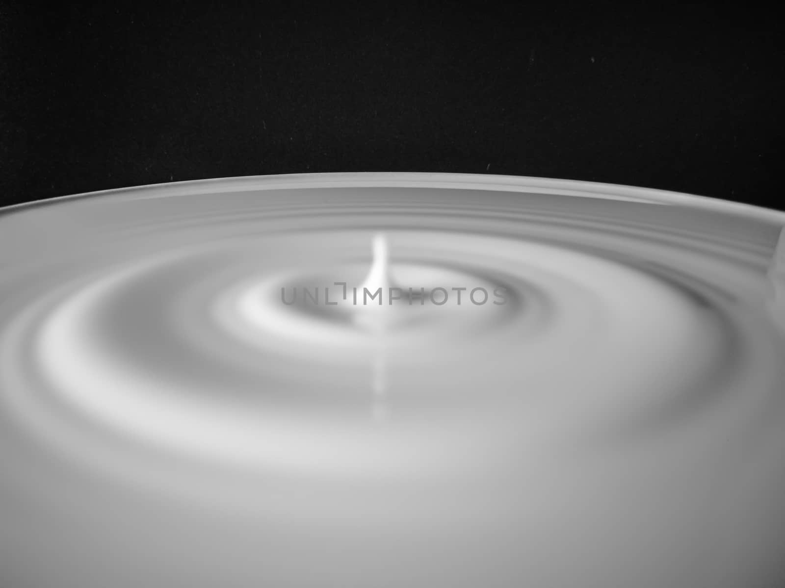 Drop of milk splashing on a black background