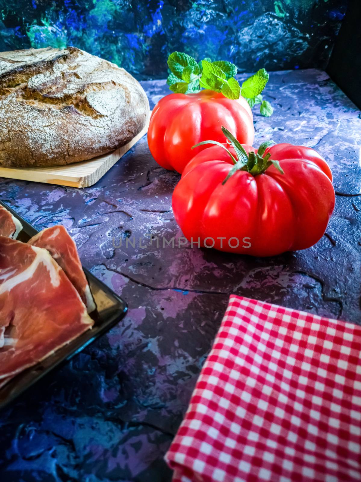 Ham, tomato, bread and herbs in composition on dark background with rough texture