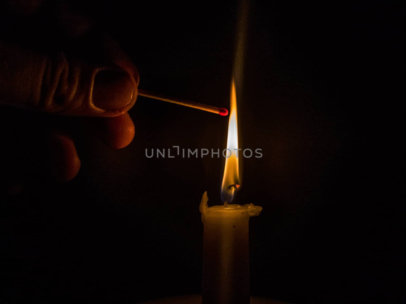 Matches burning to light a candle on black background