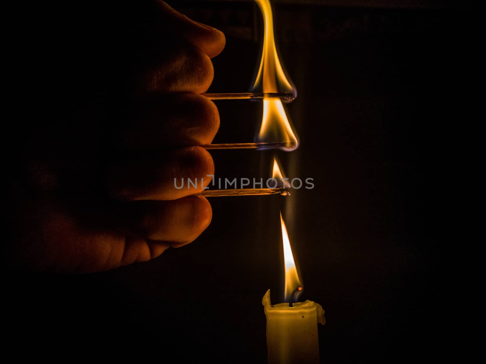 Matches burning to light a candle on black background