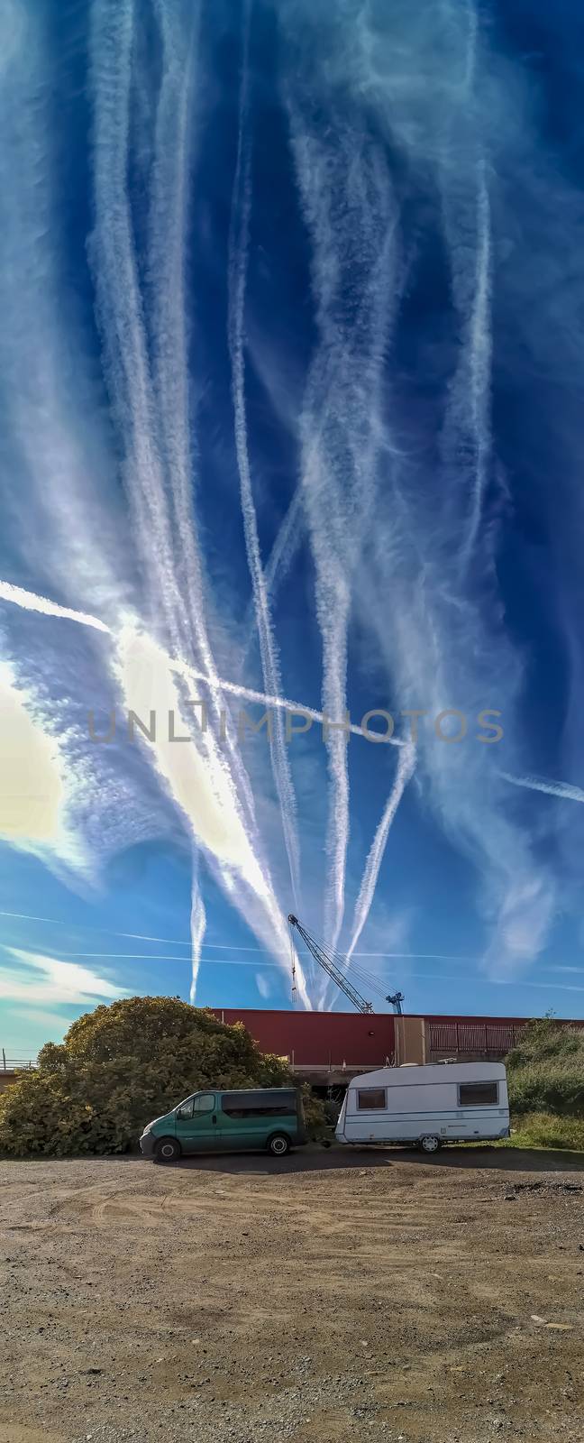 Tow caravan parked in the sand with the sky full of aircraft contrails