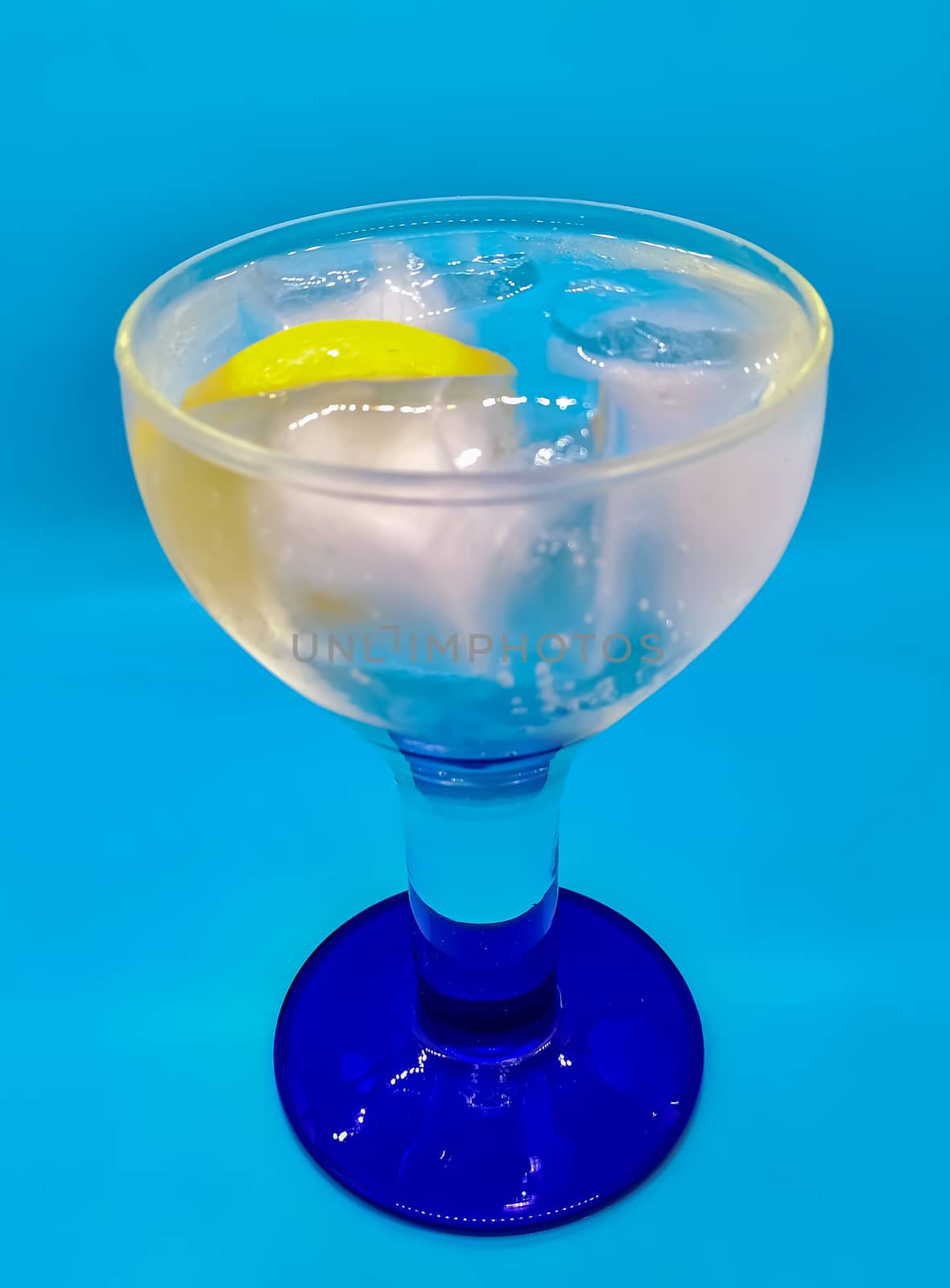Gin and tonic with a slice of lemon on blue background