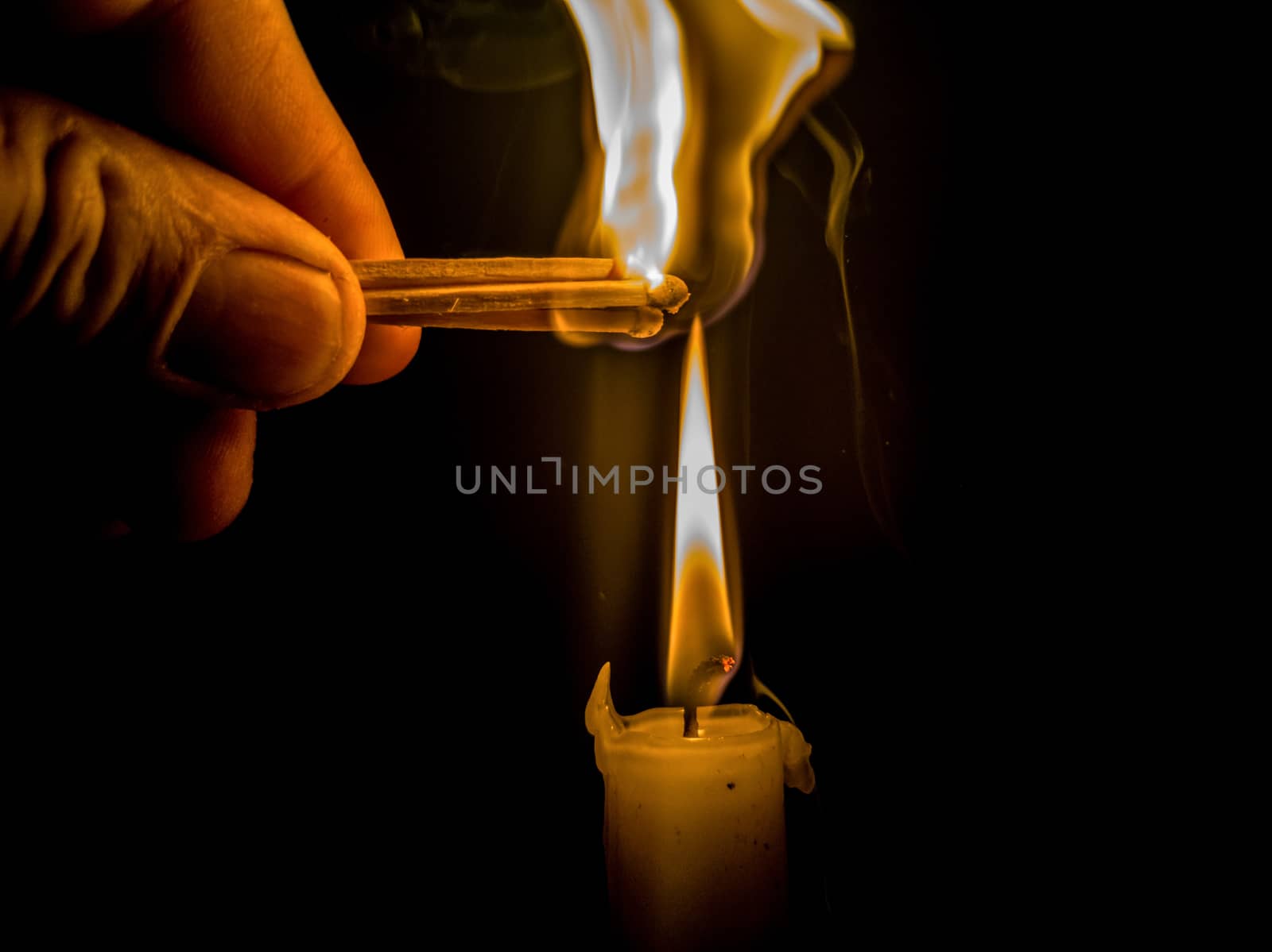 Matches burning to light a candle on black background