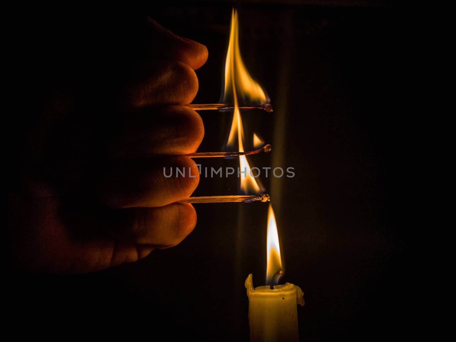 Matches burning to light a candle on black background