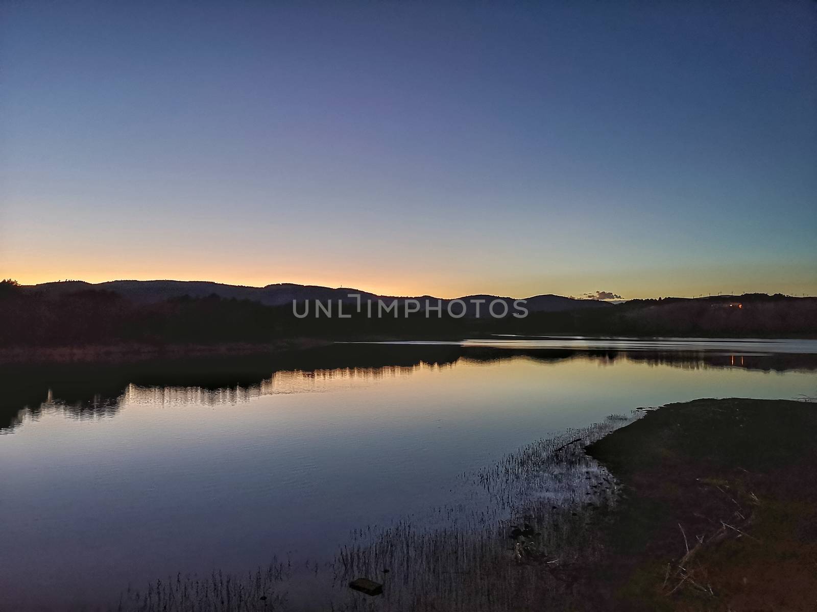 View of Puebla reservoir with mountains in the background and a pine forest