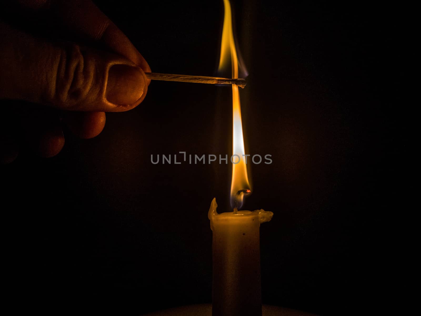 Matches burning to light a candle on black background