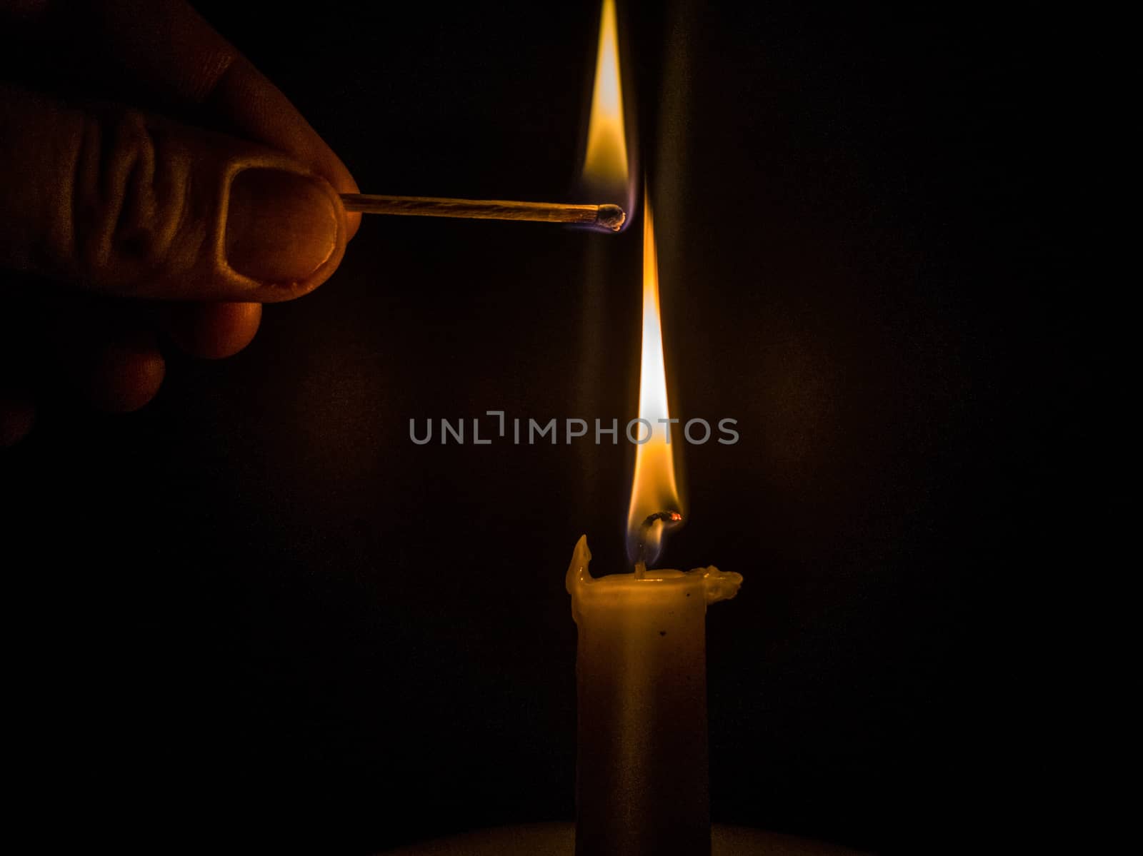 Matches burning to light a candle on black background