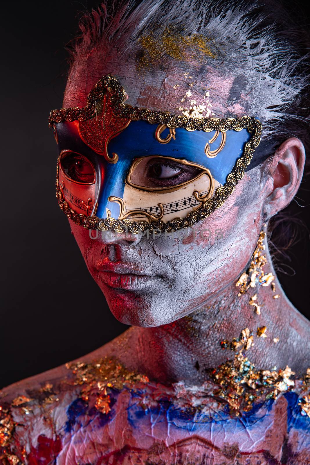 Portrait of a young masked woman with creative makeup on the theme of Venice Carnival