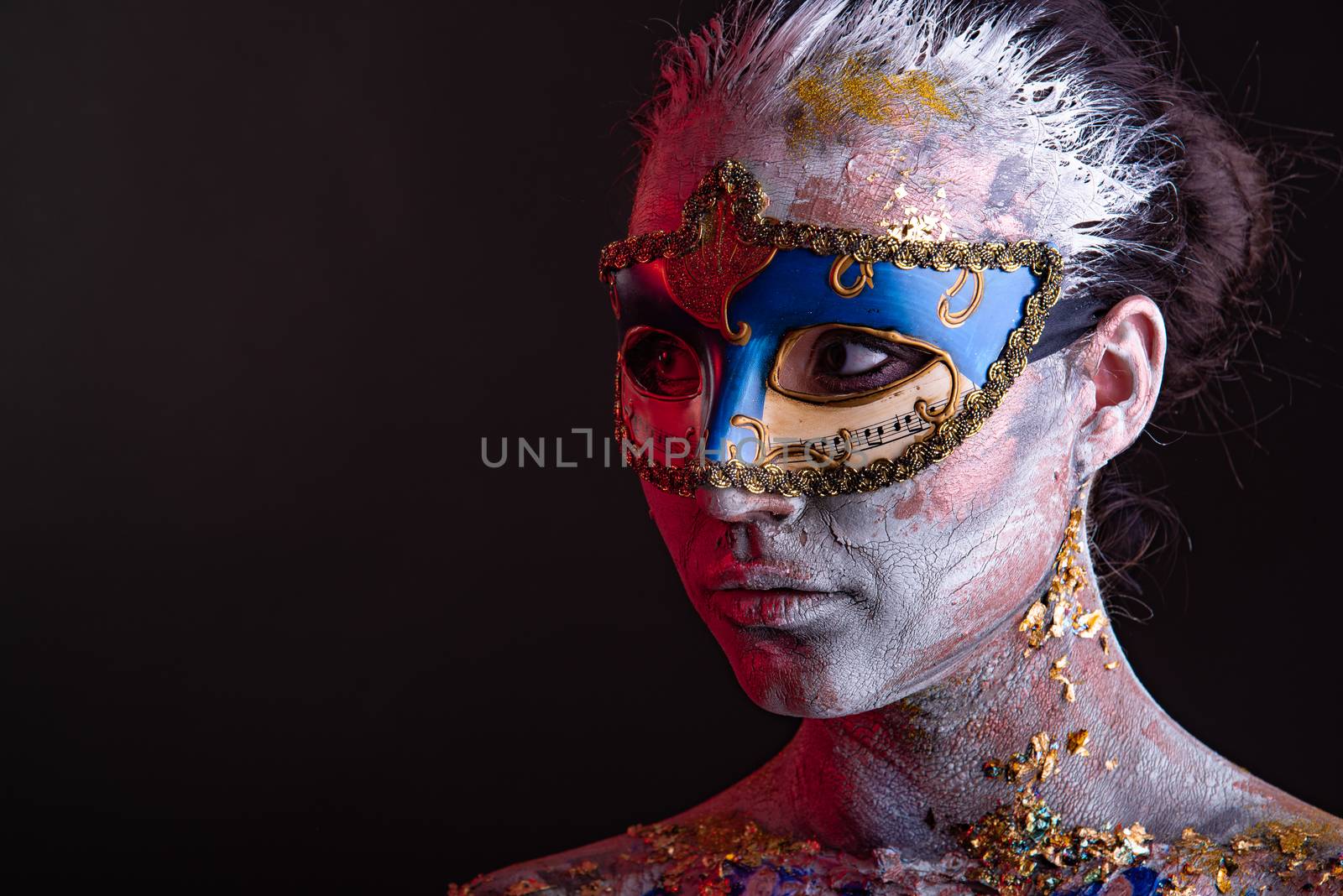 Portrait of a young masked woman with creative makeup on the theme of Venice Carnival