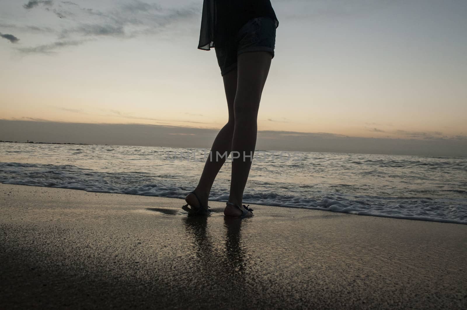 Legs of a young girl on sea and sandy beach by claire_lucia
