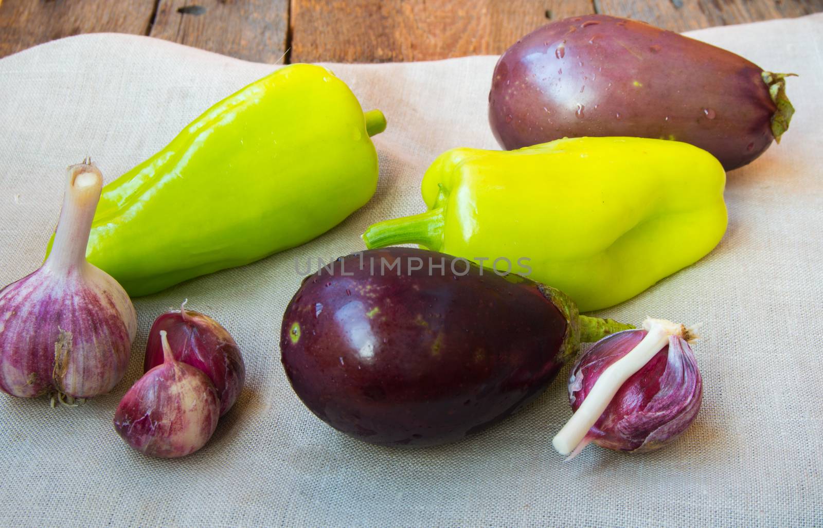 Raw eggplant, garlic, bell peppers, healthy eating and diet concept on the old wooden background.