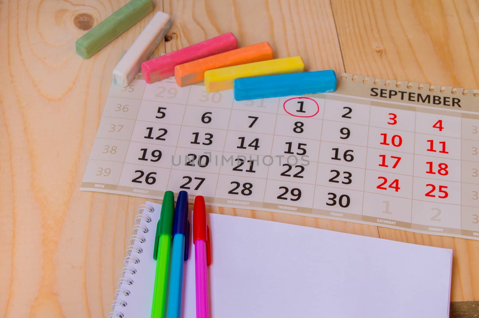 Back to school, calendar, colored chalk on wooden background.