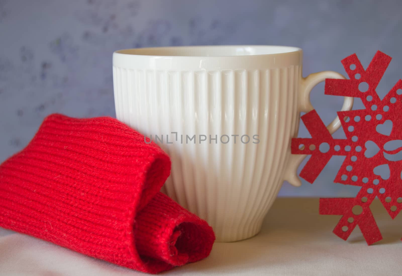 White mug and snowflake with a red knitted scarf. The Concept Of Christmas.