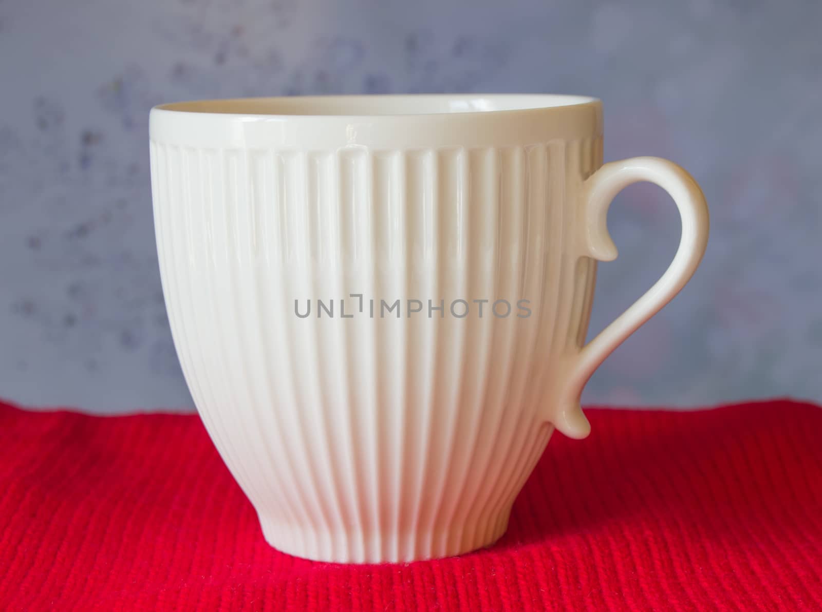 White mug stands on a red scarf, blurred blue background. Christmas by claire_lucia