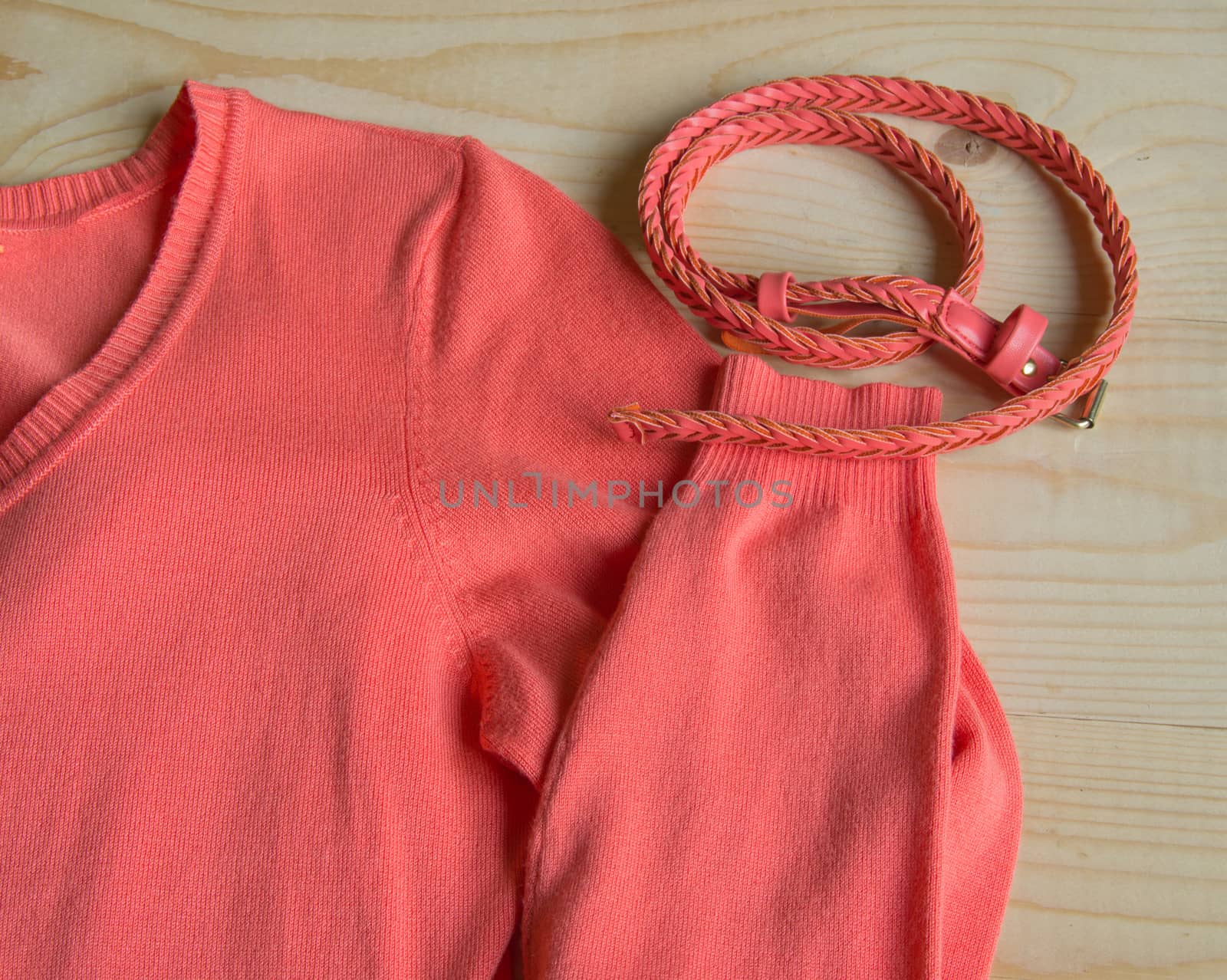 Women's fashion pink sweater with a belt on a light wooden background