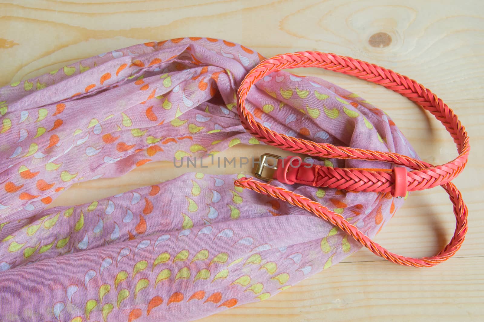 Fashionable pink accessories on wooden background - scarf, belt.