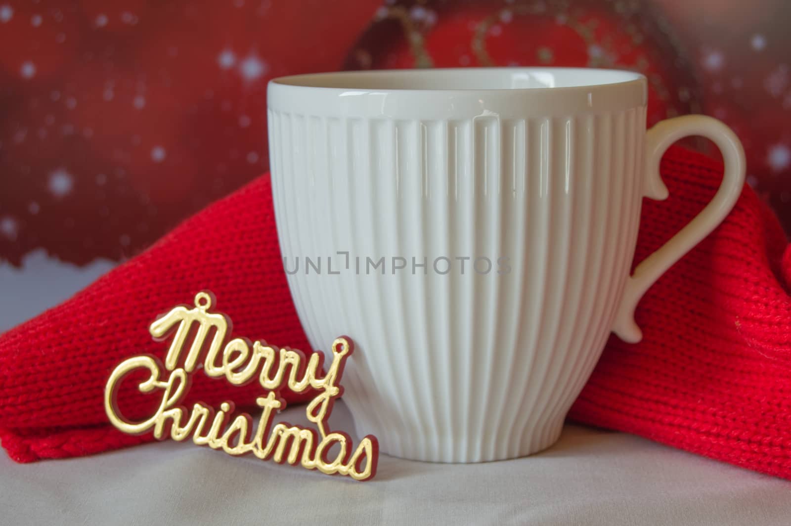 White Cup of coffee and a knitted red scarf, the words Merry Christmas.